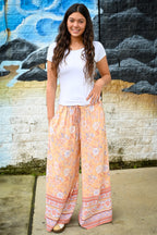 A woman wearing a white t-shirt and Meli Lounge Pants Sunrise Botanica.