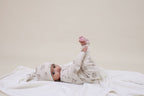 Baby lying on a white blanket wearing Aster & Oak Organic Zip Romper  Byron Bear Onesie
