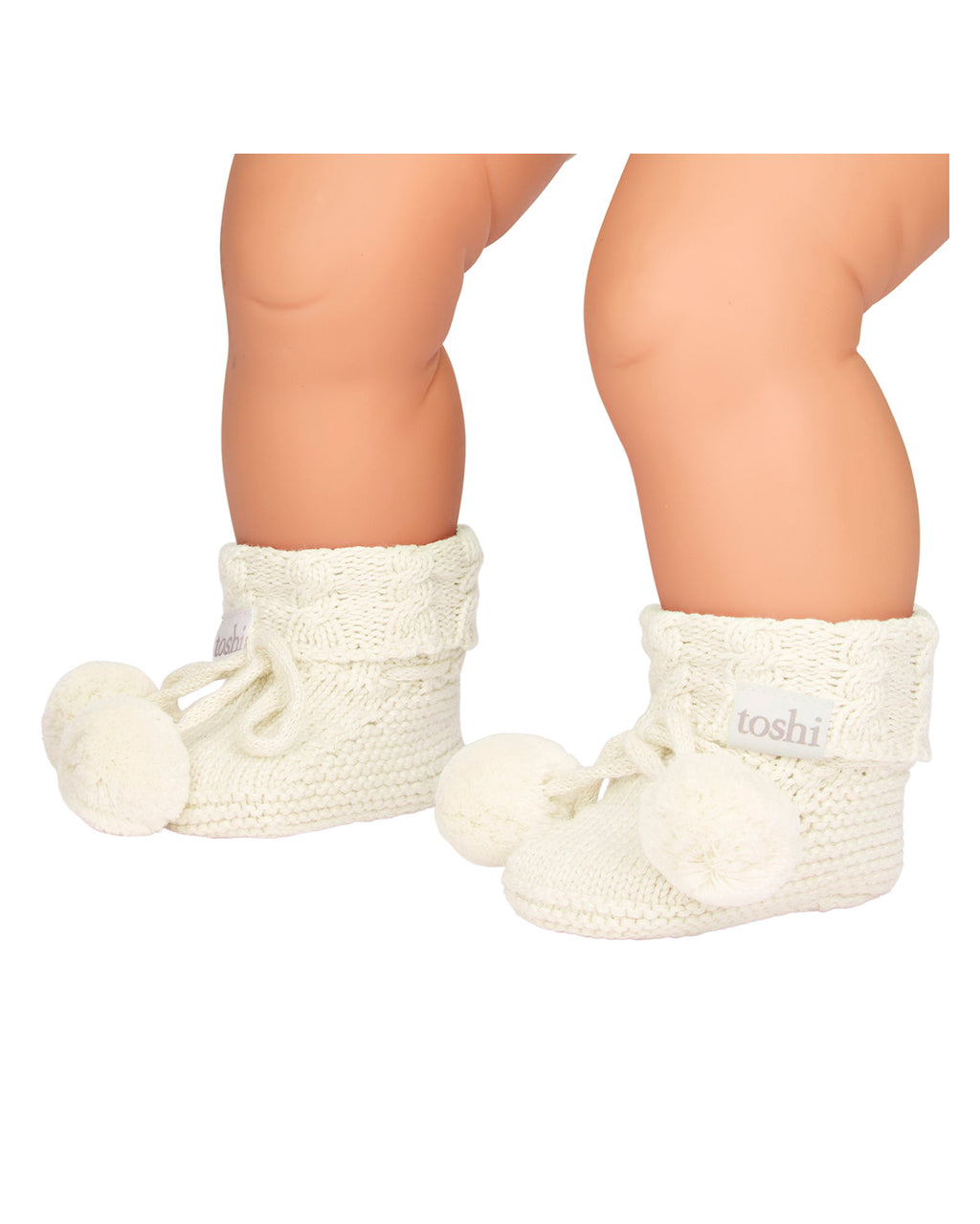 baby wearing a cream, a knitted cream white organic baby booties with pom-pom on a white background.