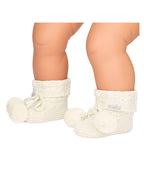 baby wearing a cream, a knitted cream white organic baby booties with pom-pom on a white background.