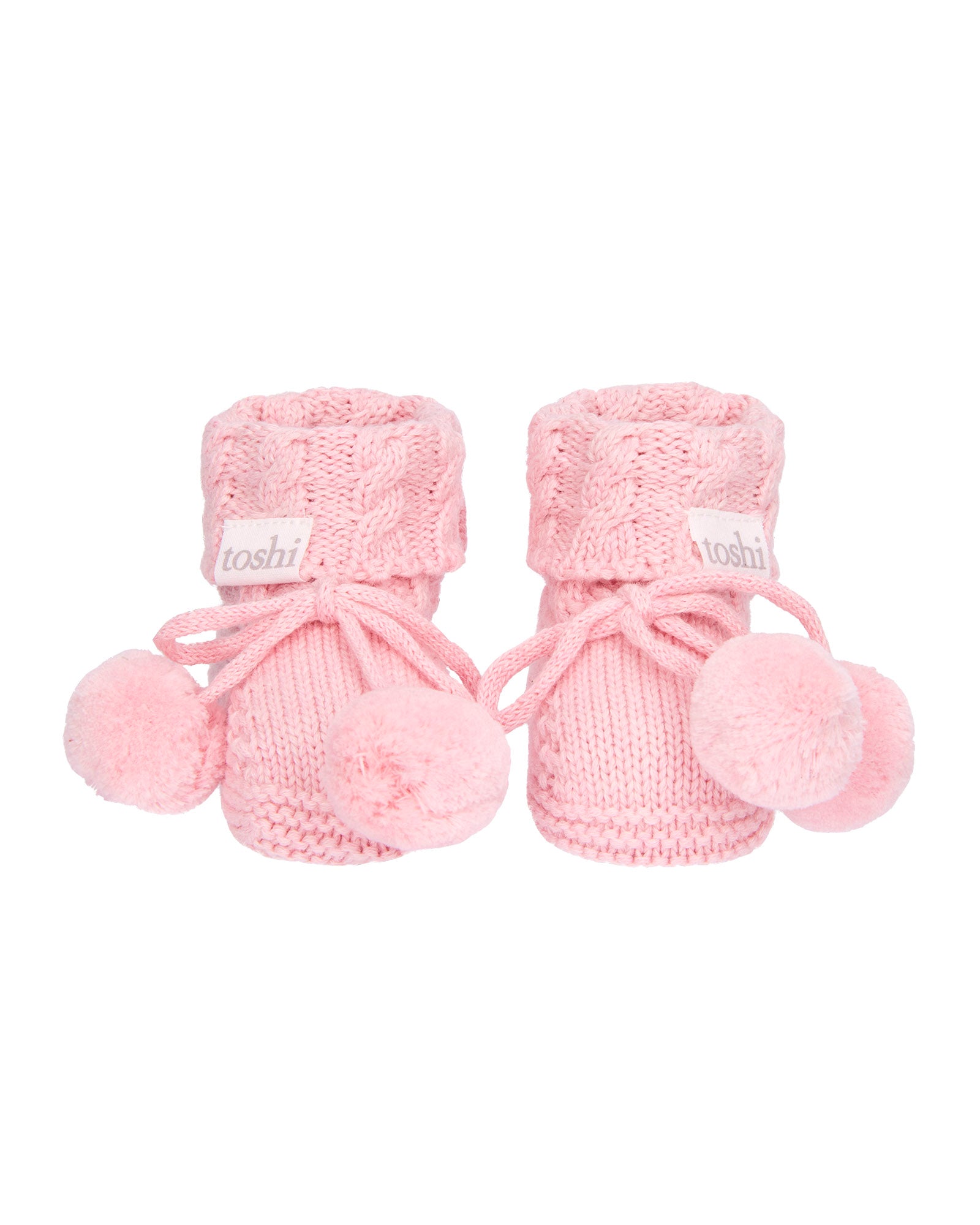 Misty Rose, a Pink knitted baby booties with pom-poms on a white background