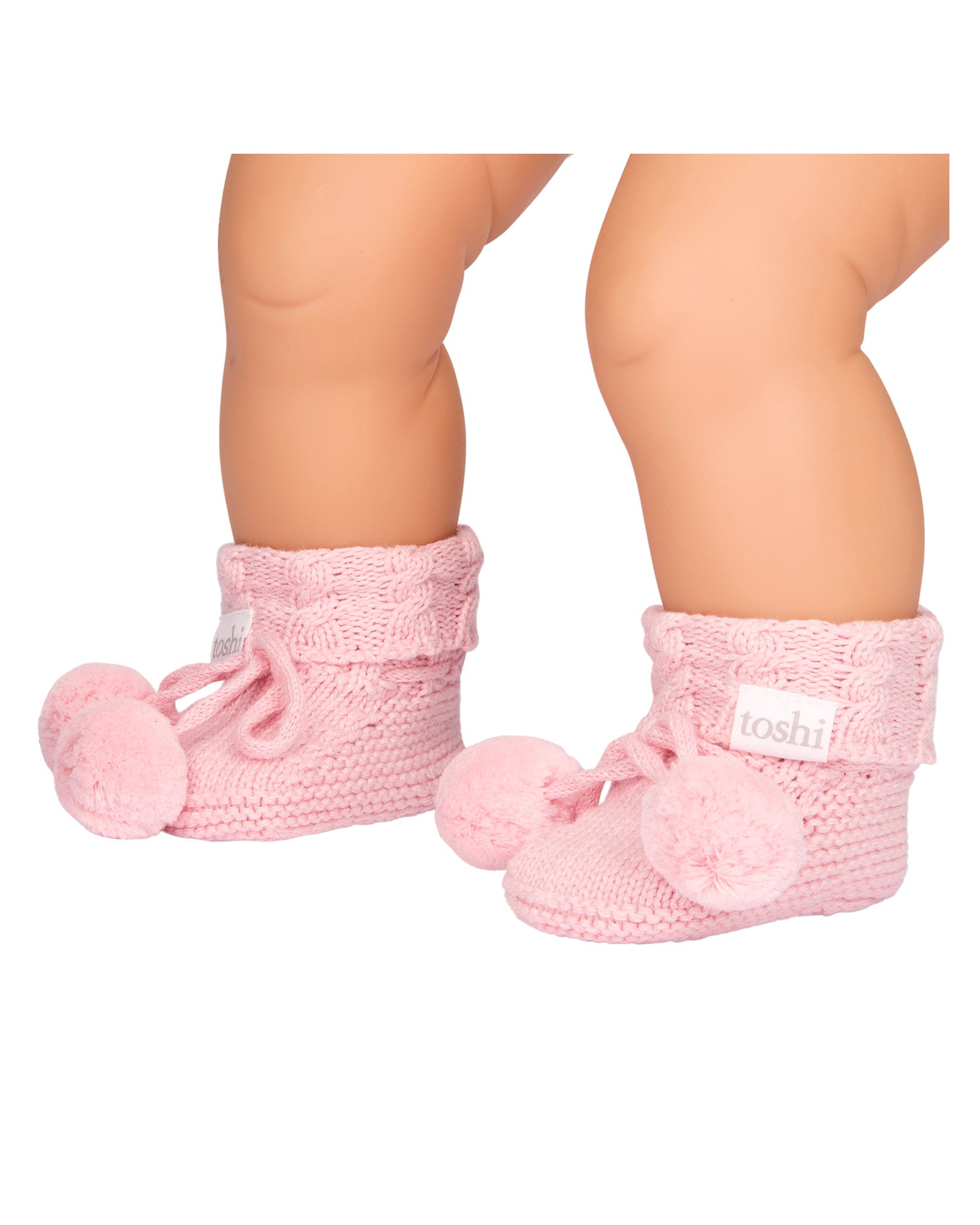 Baby wearing a Misty Rose, a Pink knitted baby booties with pom-poms on a white background