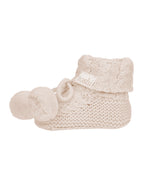 Oatmeal, a Pair of beige knitted baby booties with pom-poms on a white background.