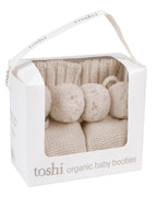 Oatmeal, a Toshi organic beige baby booties on a packaging with a white background.