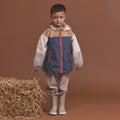 Child wearing the Crywolf Packable Jacket Ash Colourblock and pants standing next to a bale of hay on a brown background