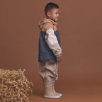 Child wearing the Crywolf Packable Jacket Ash Colourblock and pants standing next to a bale of hay on a brown background