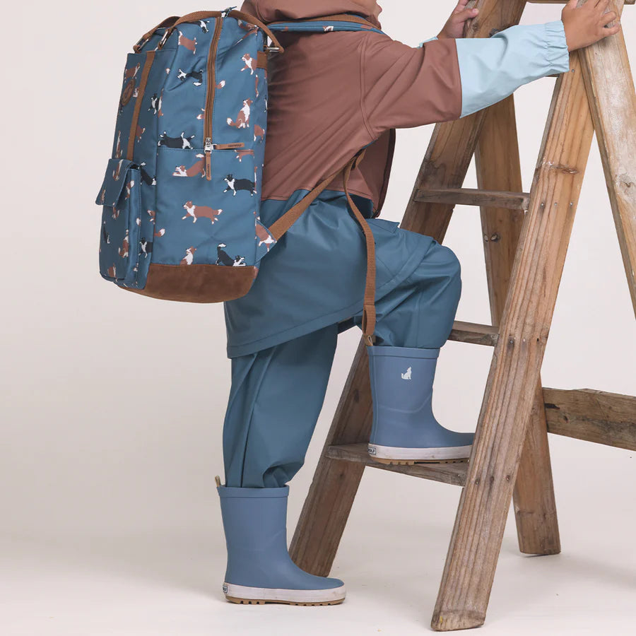 Person wearing a blue raincoat, pants, and boots with a backpack wearing a pair of Rain Boots Highland Blue. 