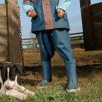 Person wearing blue raincoat and Crywolf Rain Boots Highland Blue standing next to a dog in an outdoor setting.