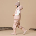 Child wearing a pink winter outfit with a vest, pants, and Crywolf Rain Boots on a beige background