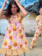Two young girls in matching Sundaisy print, a vintage floral pattern in mustard yellow, rust orange, and dusty pink.