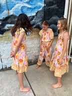 Three young girls in matching Sundaisy print, a vintage floral pattern in mustard yellow, rust orange, and dusty pink.
