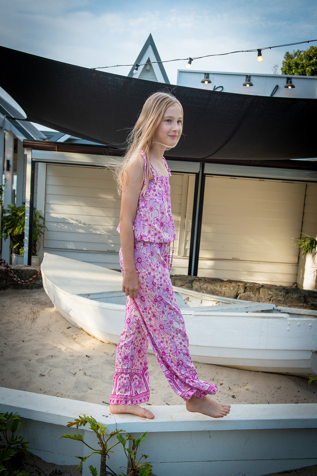 Lifestyle shot featuring a child in a bohemian-style sleeveless jumpsuit in Lilac haze print, a vibrant shades of magenta, pink, and cream, highlighting the soft, earthy color palette.