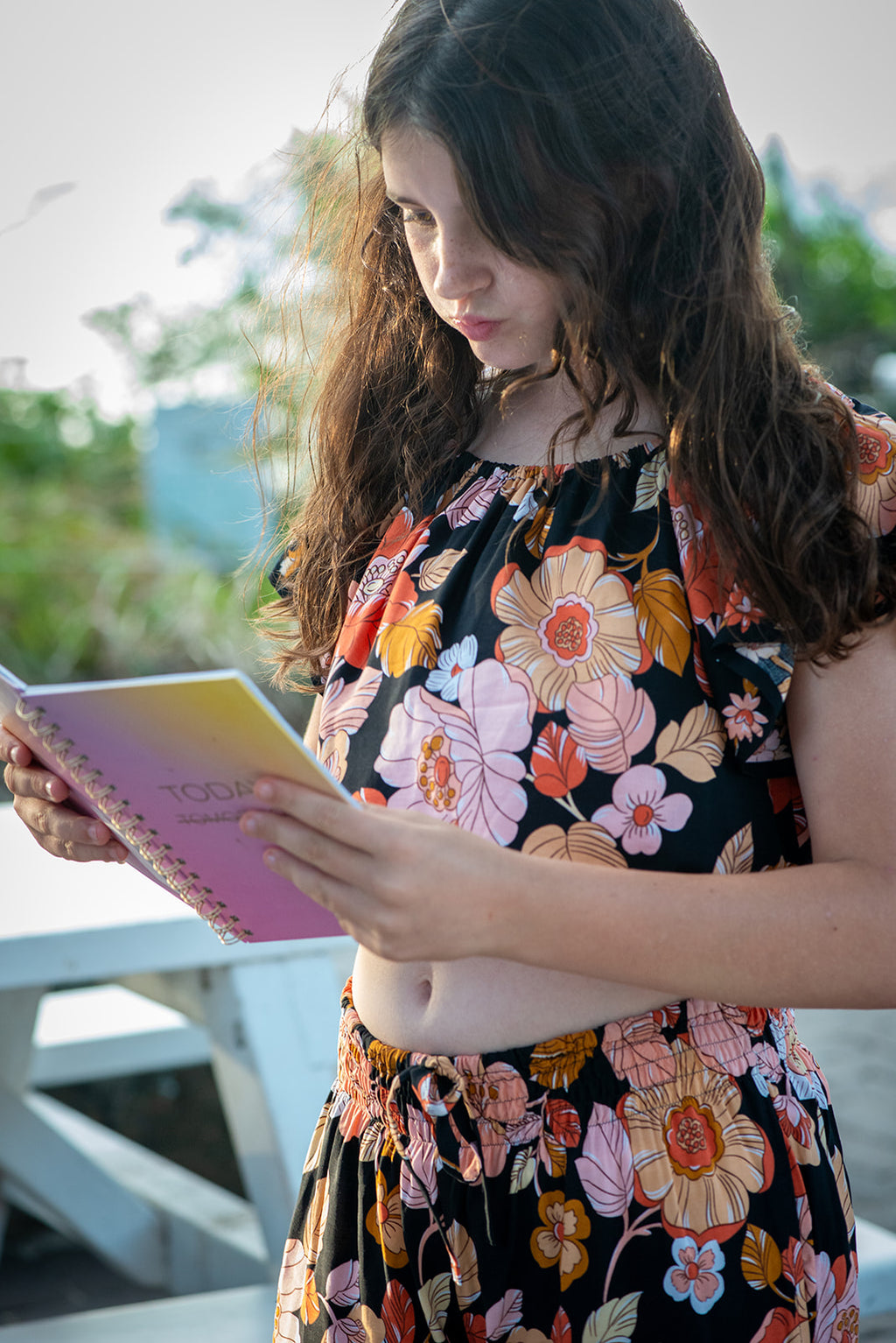 Girl wearing a black two-piece set featuring a short-sleeve top and wide-leg pants with Wild Dahlia print, a bold retro floral print in warm orange, mustard, and peach.
