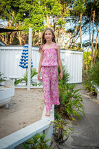 Lifestyle shot featuring a child in a bohemian-style sleeveless jumpsuit in Lilac haze print, a vibrant shades of magenta, pink, and cream, highlighting the soft, earthy color palette.