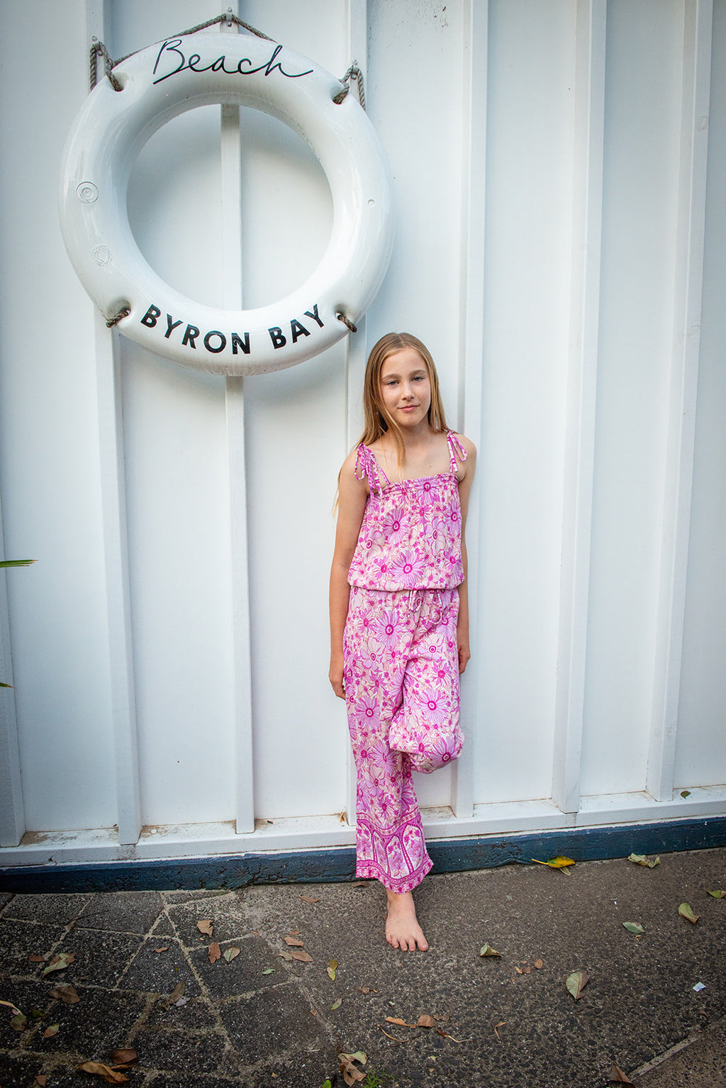 Lifestyle shot featuring a child in a bohemian-style sleeveless jumpsuit in a Lilac haze print, a vibrant shades of magenta, pink, and cream, highlighting the soft, earthy color palette.