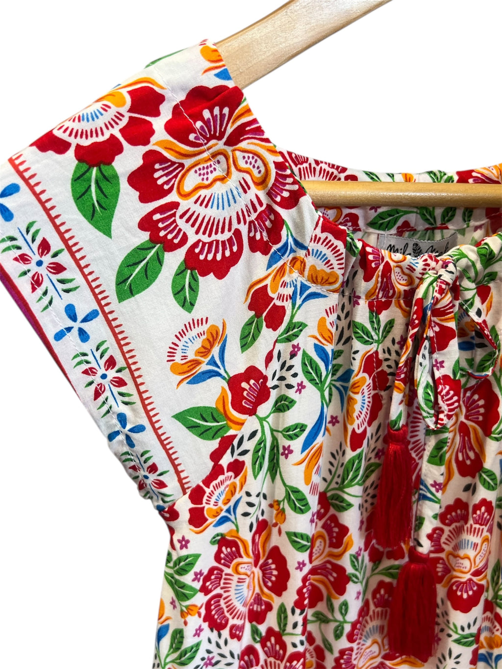 Floral dress featuring Fiesta Bloom print, a white base with a vibrant floral pattern in red, orange, green, and blue.
