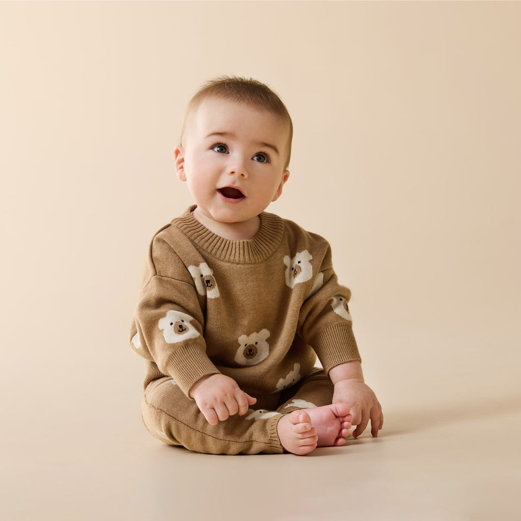 Baby wearing a Wilson & Frenchy Organic Knitted Jacquard Jumper a brown sweater with bear patterns.