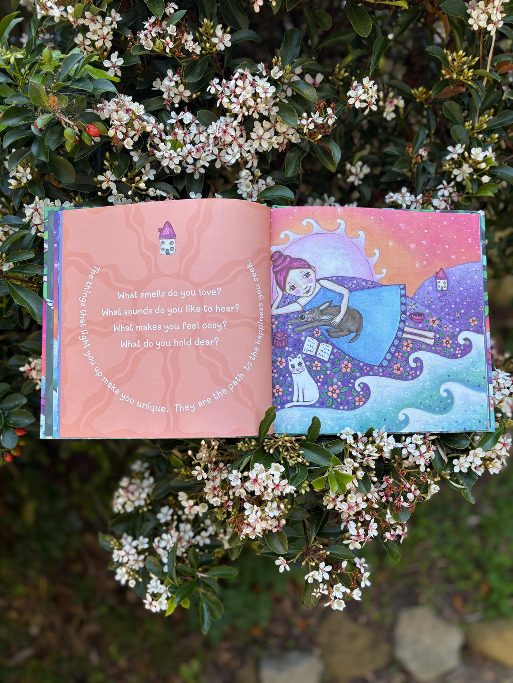 Open book with colorful illustrations and text, surrounded by flowers and greenery