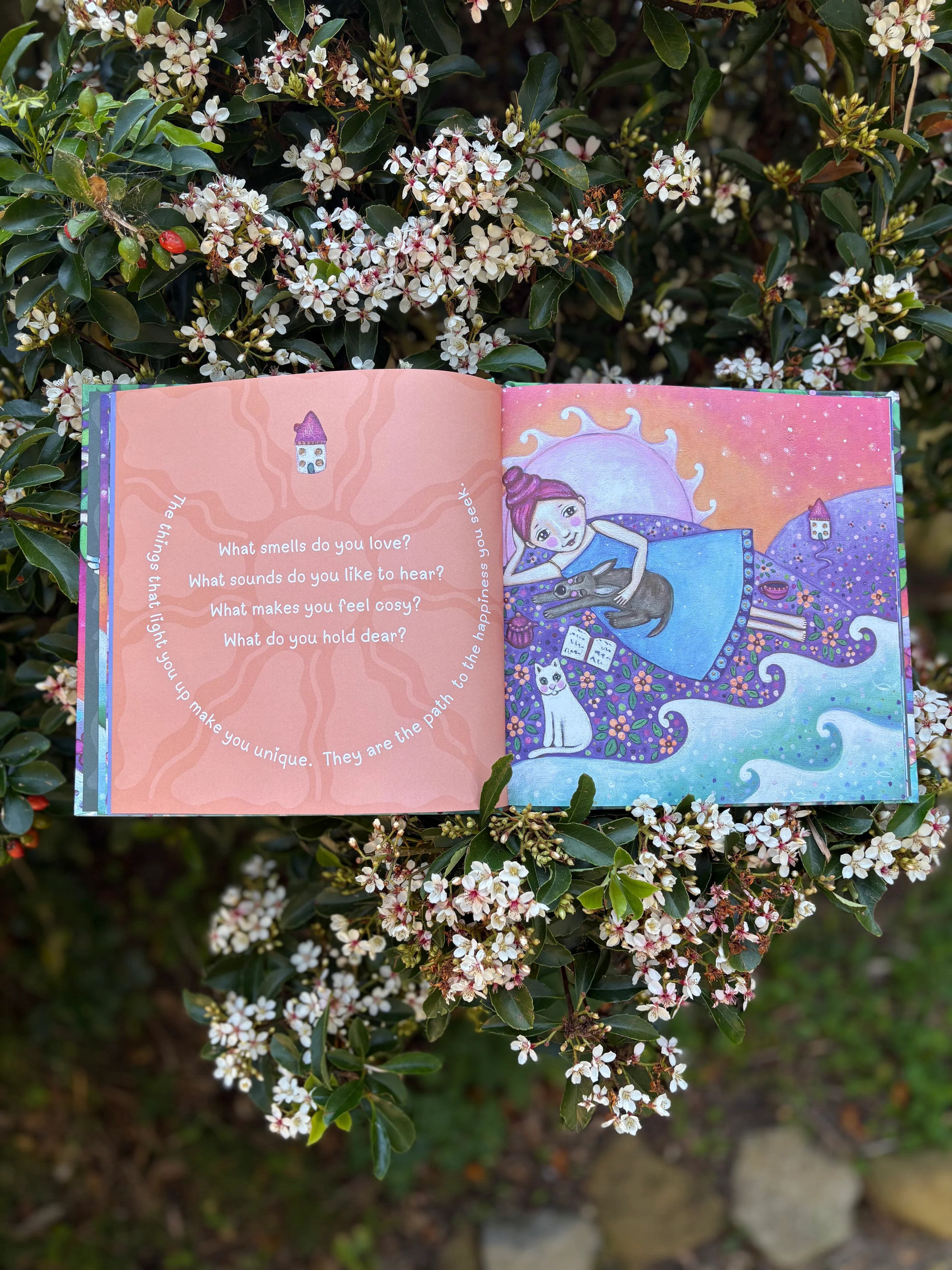 Open book with colorful illustrations and text, surrounded by flowers and greenery