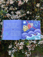 Open book with colorful illustrations and text, surrounded by flowers