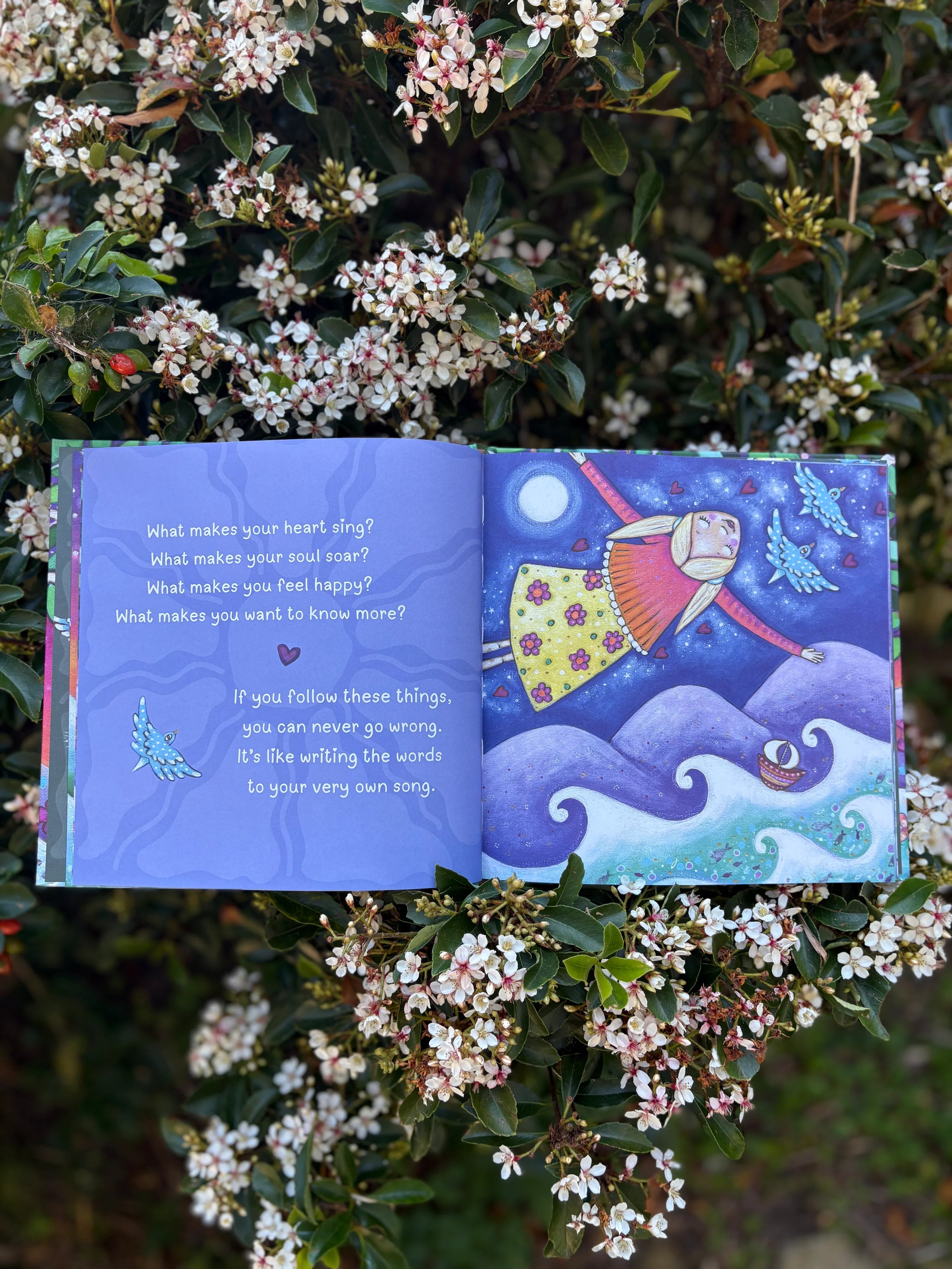 Open book with colorful illustrations and text, surrounded by flowers