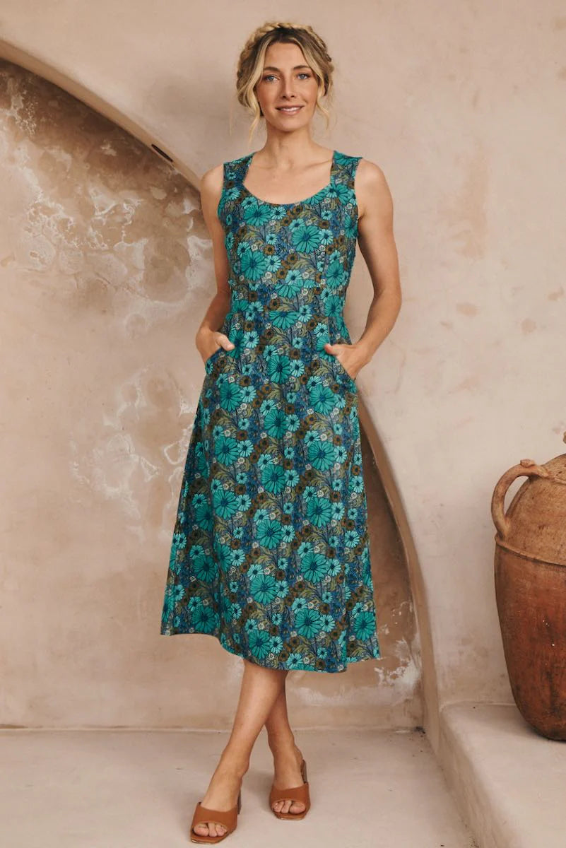 Woman wearing a floral Bianca Midi Dress in Bluebell dress standing against a textured wall.