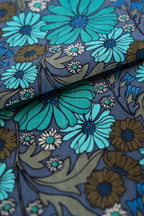 Close-up of floral fabric of Bianca Midi Dress, a blue and green flowers on a dark background